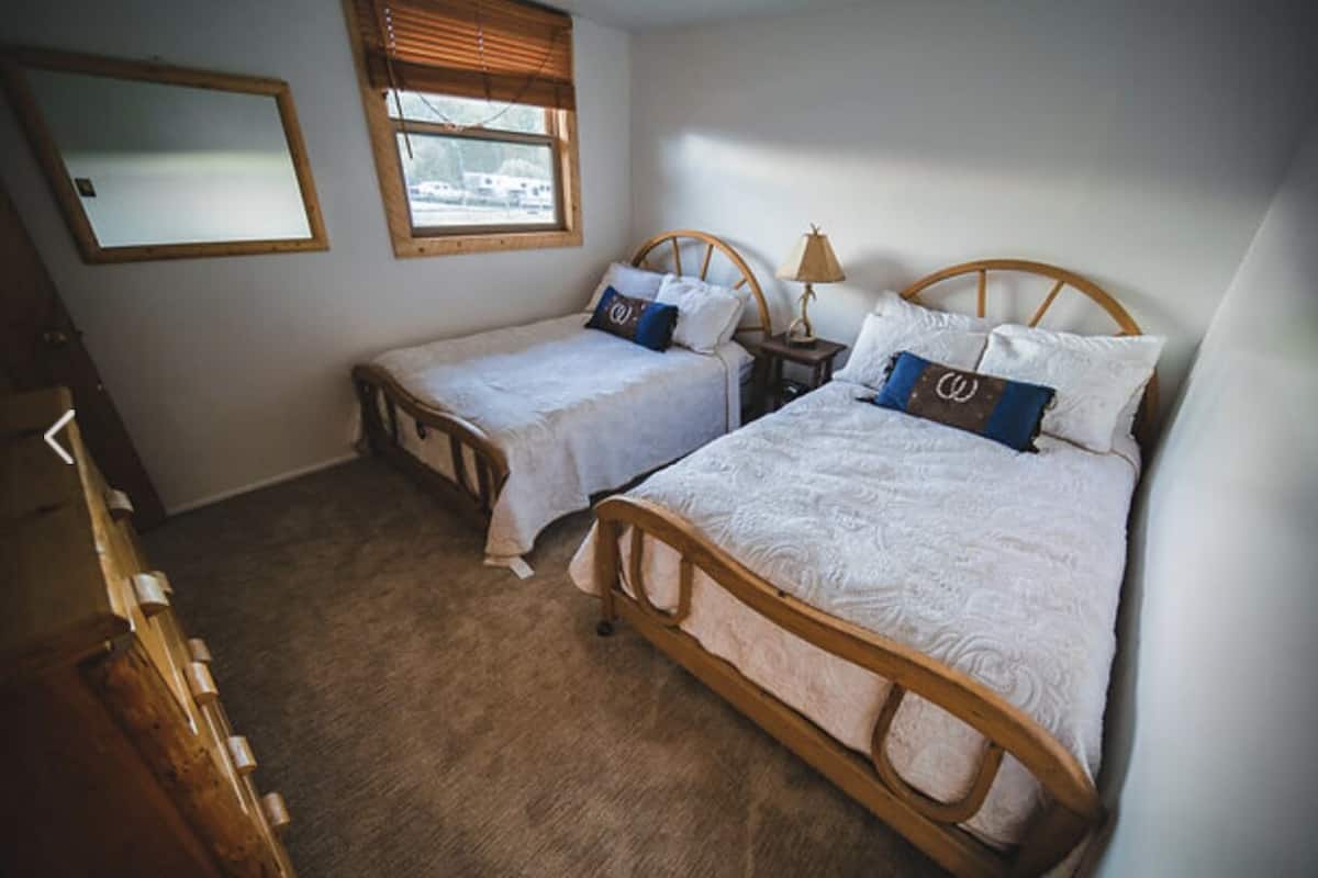 Ein Schlafzimmer mit zwei Holzbett, einem Spiegel und einem Fenster.