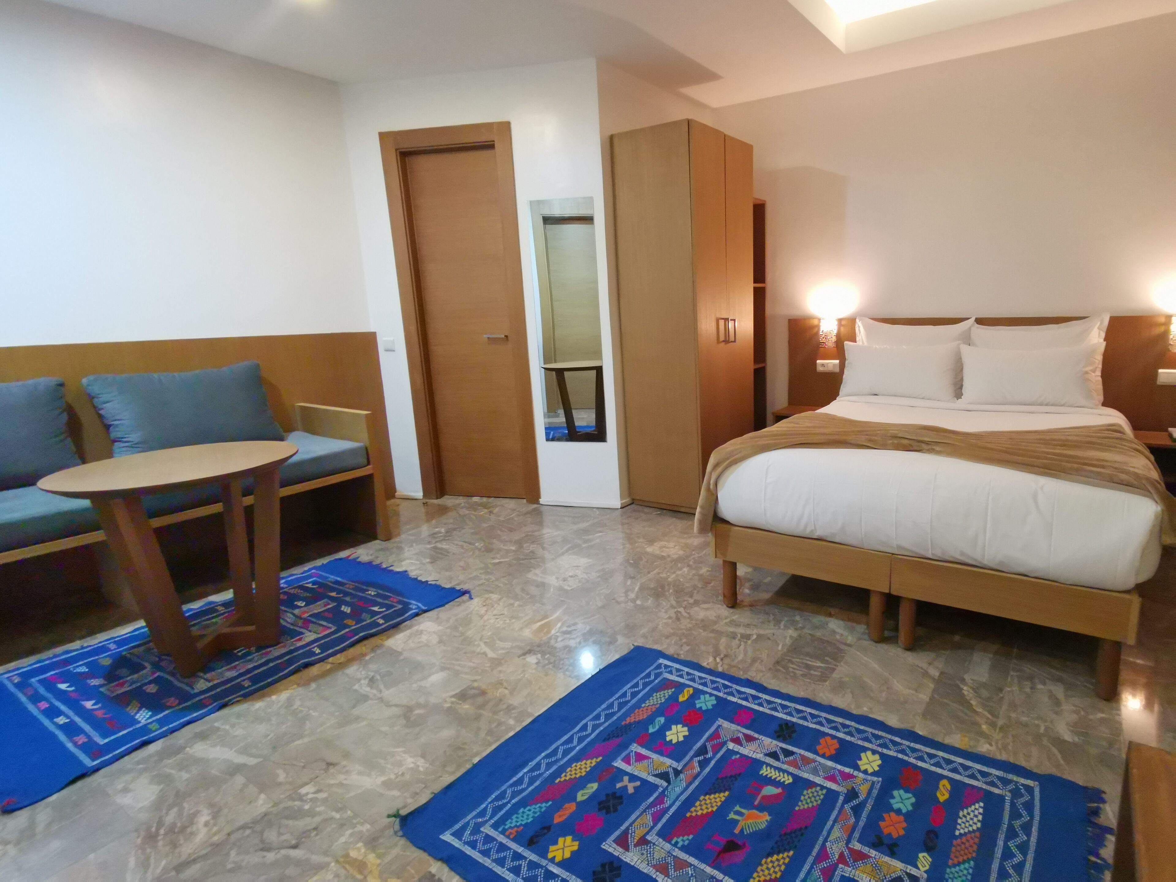 A hotel room with a bed, a sofa, a small table, and a wardrobe.