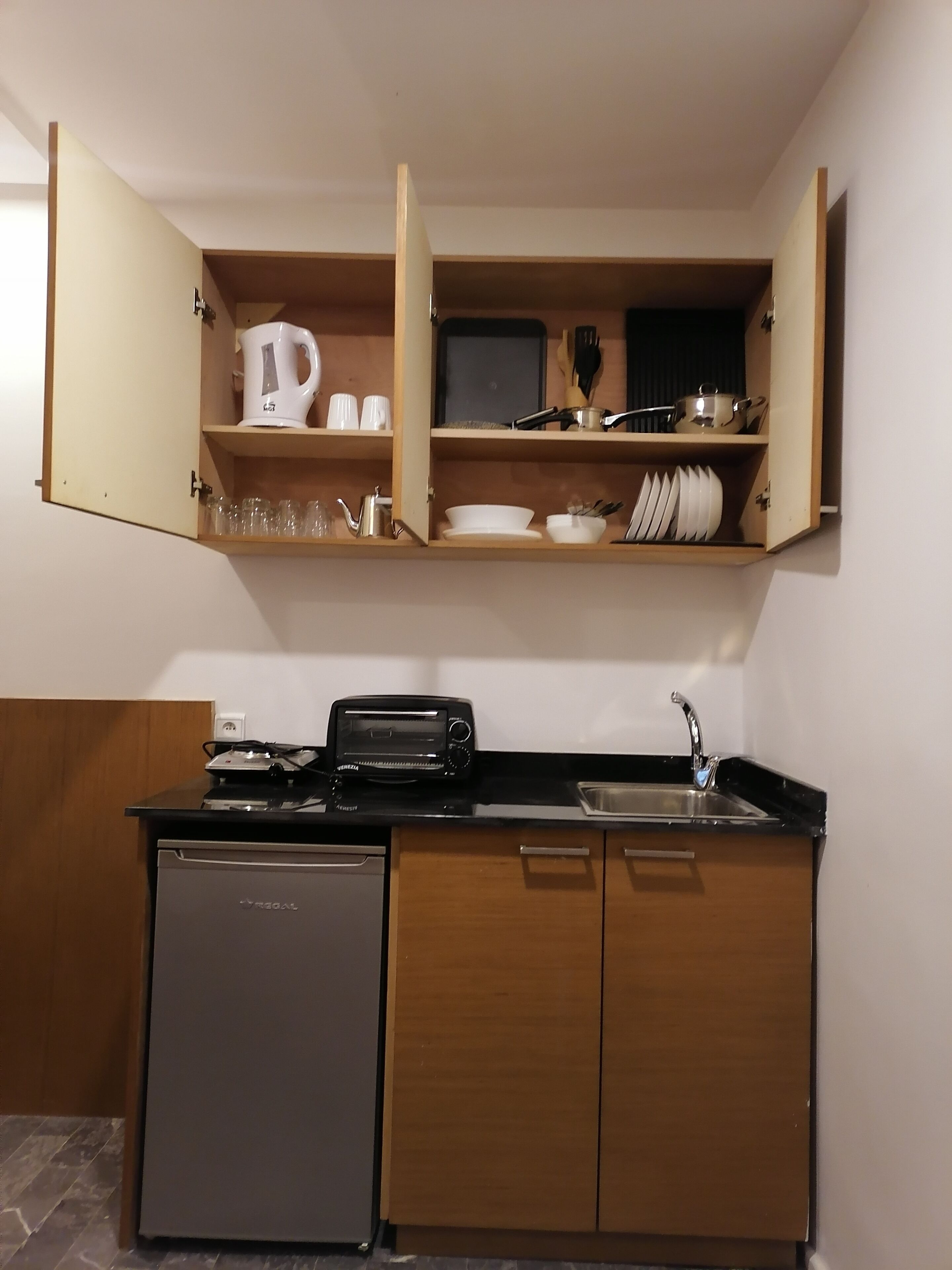 A compact kitchen with a built-in dishwasher, a toaster, and a sink.