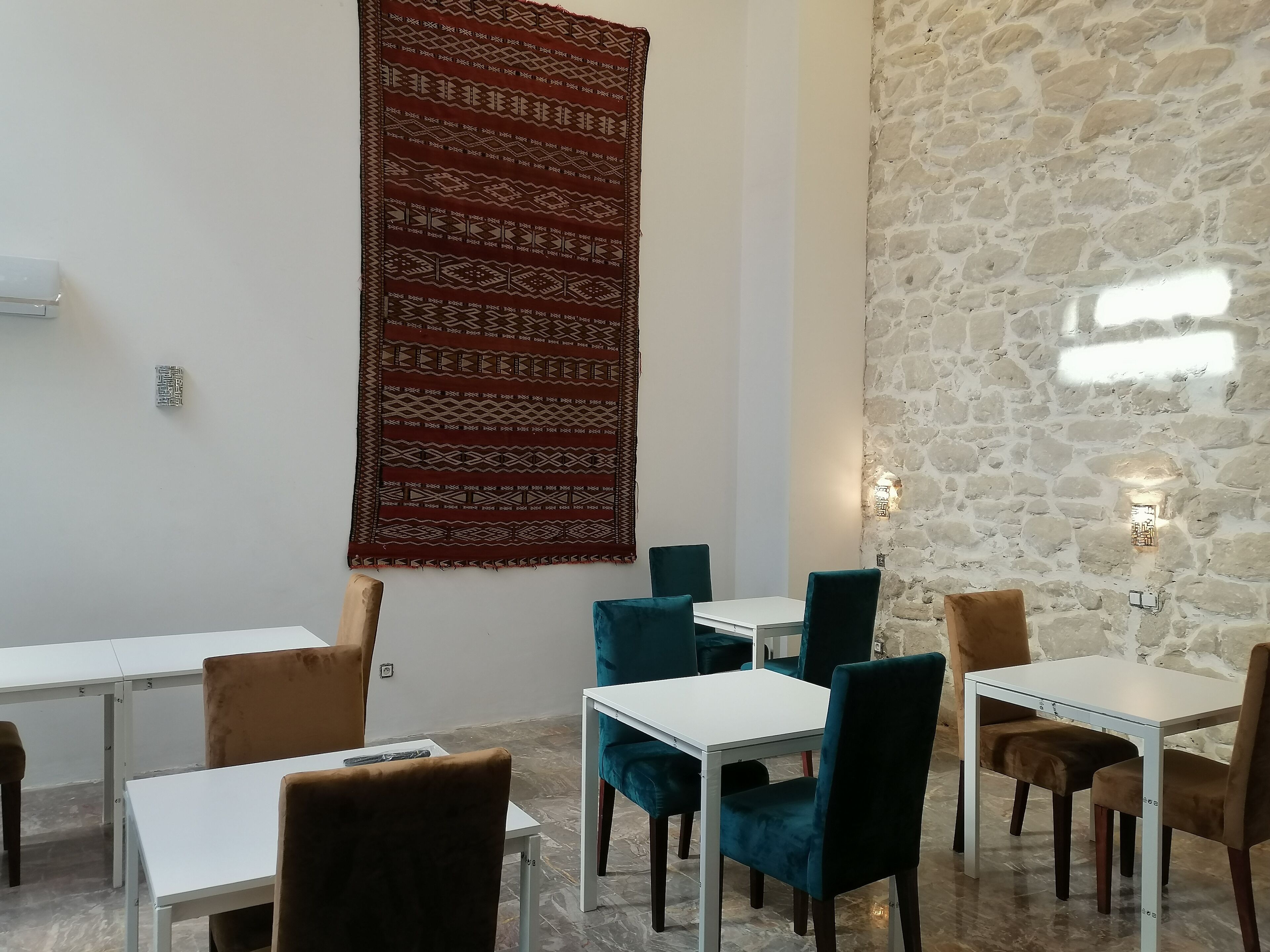 Uma sala de jantar com parede de pedra, tapete estampado e móveis modernos.