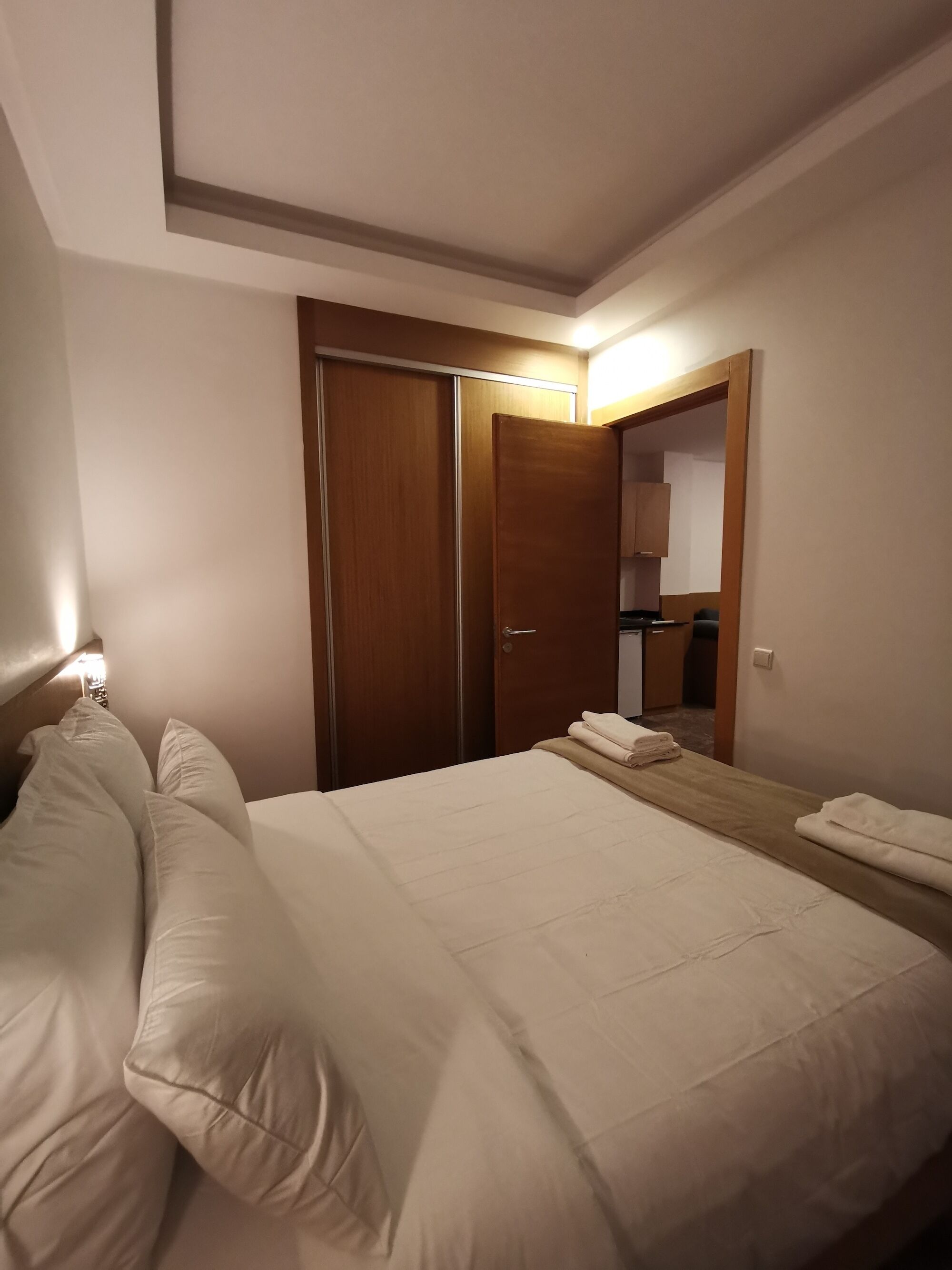 Une chambre d’hôtel avec un lit, une table de chevet, une armoire en bois et un miroir.