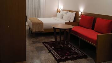 Une chambre d’hôtel avec un lit, un canapé, une petite table et un banc en bois.