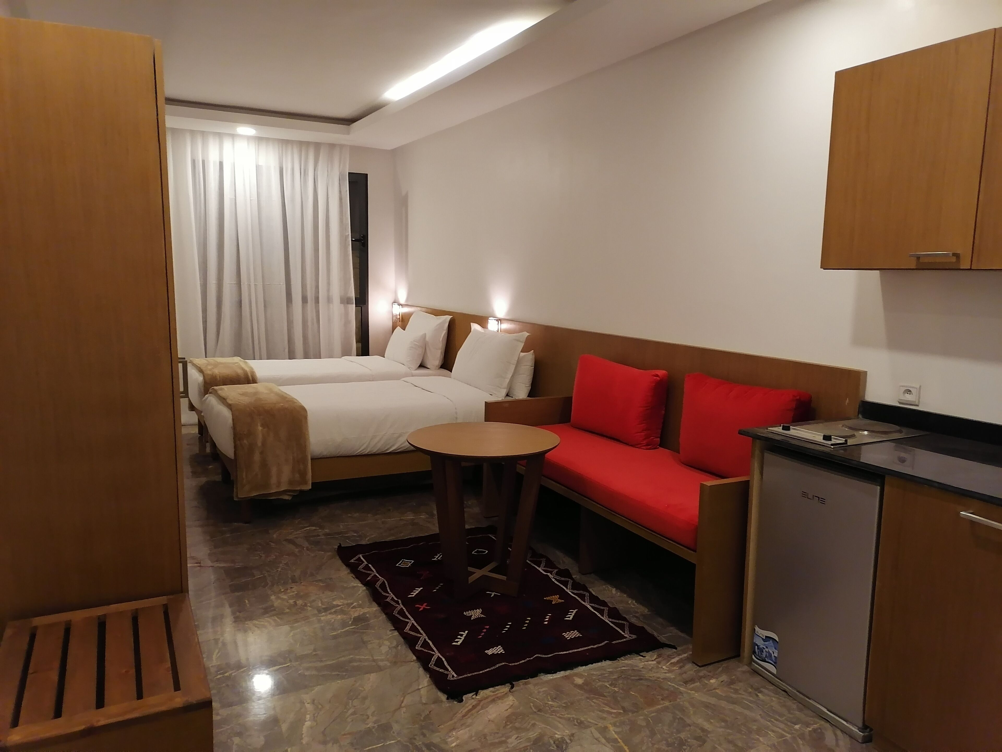 A hotel room with a bed, a sofa, a small table, and a kitchenette.