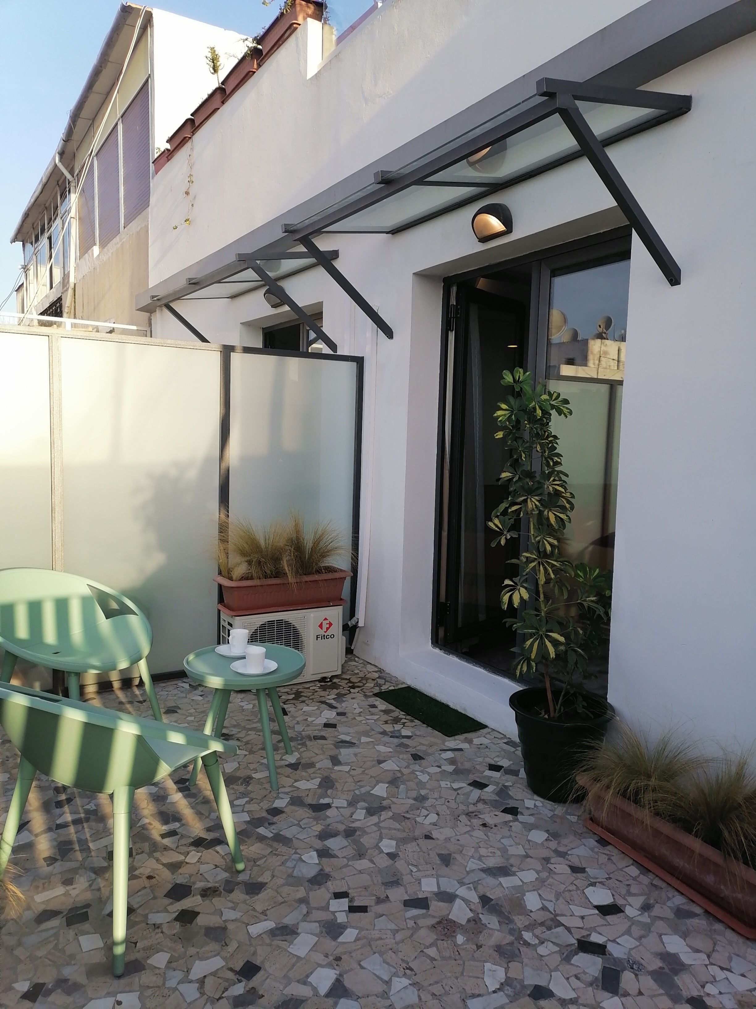 A patio area with a tiled floor, a table with chairs, and potted plants.