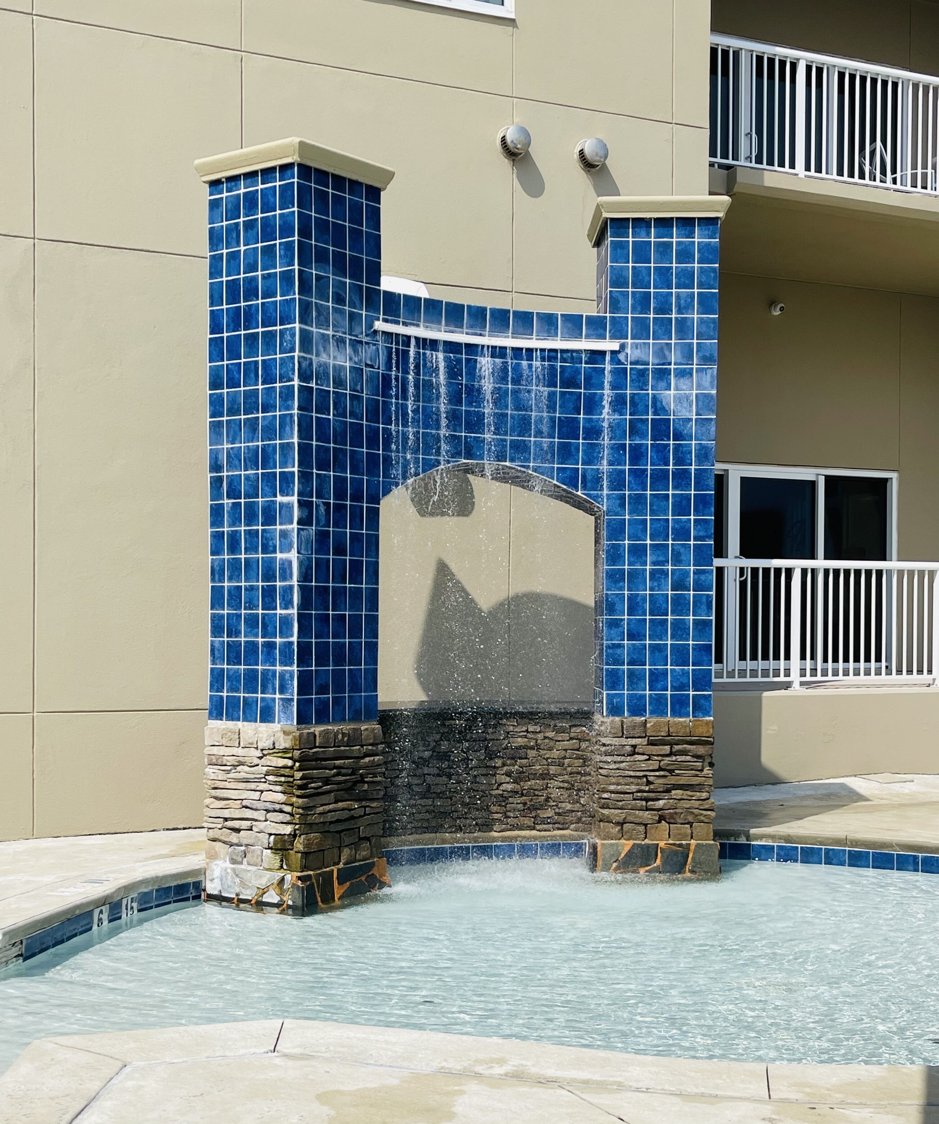 Una piscina con un muro in piastrelle blu e una struttura in pietra.