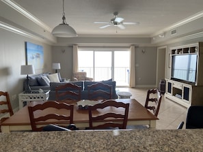 A living room with a dining table, chairs, a sofa, a TV, and a ceiling fan.