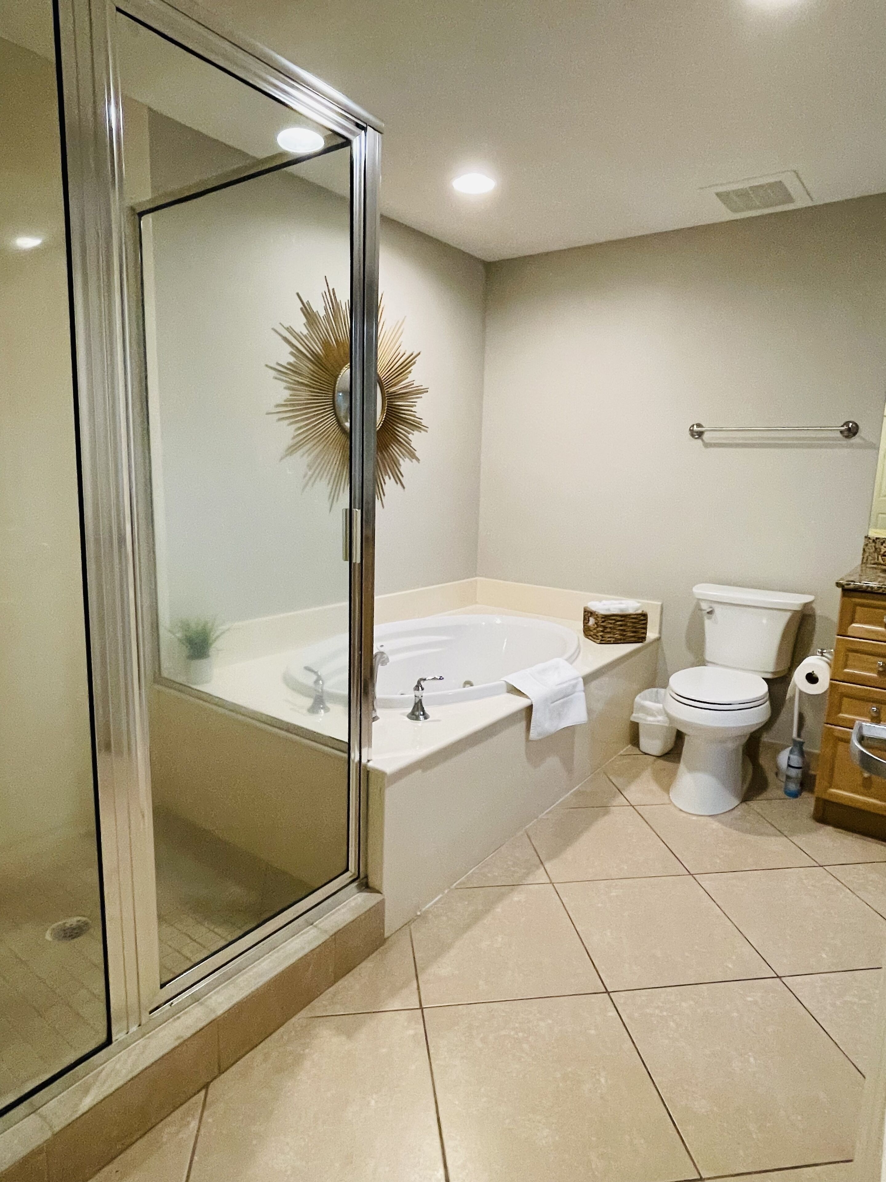 Un baño moderno con cabina de ducha de vidrio, una bañera independiente, un inodoro y un lavamanos con espejo.