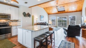 Une cuisine spacieuse avec des armoires blanches, un grand îlot central et un ventilateur de plafond.