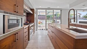 Eine moderne Küche mit Edelstahlgeräten, Holzschränken und einer großen Kochinsel mit Spüle.