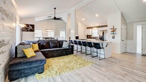 A spacious living area with a dark gray sectional sofa, a yellow rug, and a kitchen in the background. - Dock, Deck & Views! Lakefront Retreat in Camdenton (Camdenton)