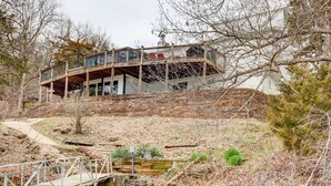 A two-story house with a balcony, a wooden deck, and a small bridge over a stream. - Dock, Deck & Views! Lakefront Retreat in Camdenton (Camdenton)