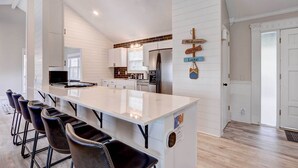 A modern kitchen with a central island, bar stools, and a sign indicating a lake view. - Dock, Deck & Views! Lakefront Retreat in Camdenton (Camdenton)