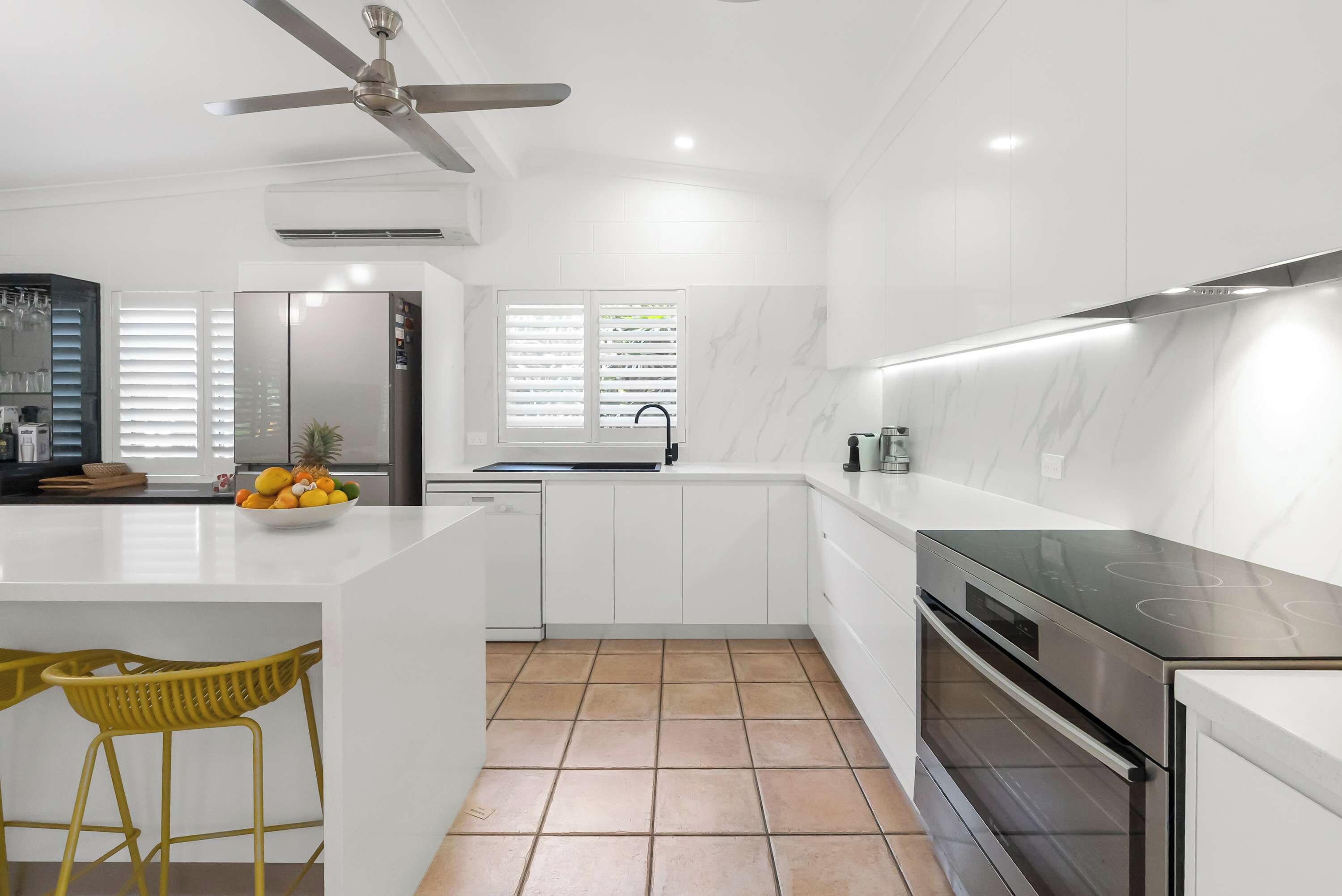 A modern kitchen with white cabinetry, a built-in oven, and a stainless steel range hood.