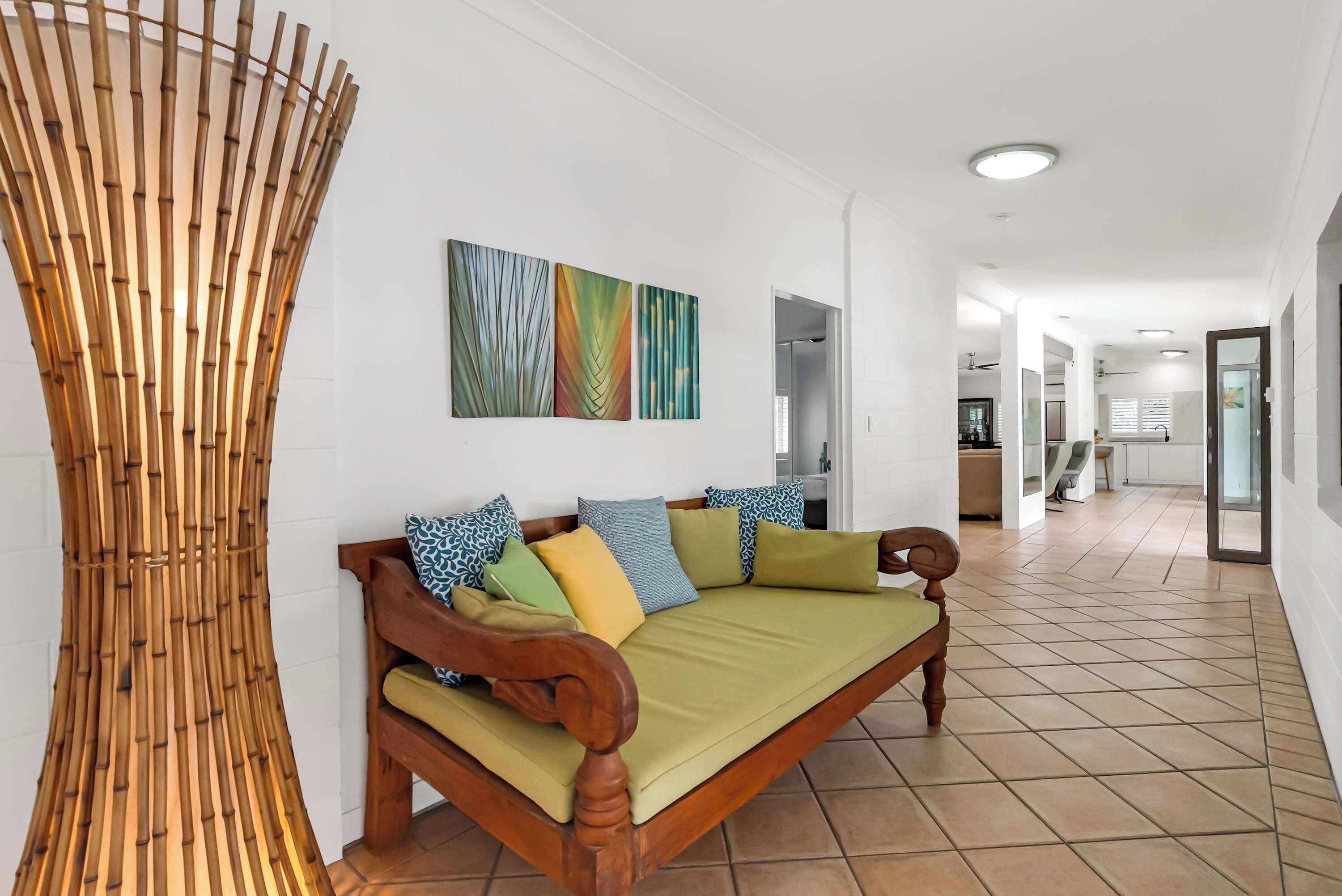 A modern living room with a wooden sofa, a bamboo wall decoration, and abstract wall art.