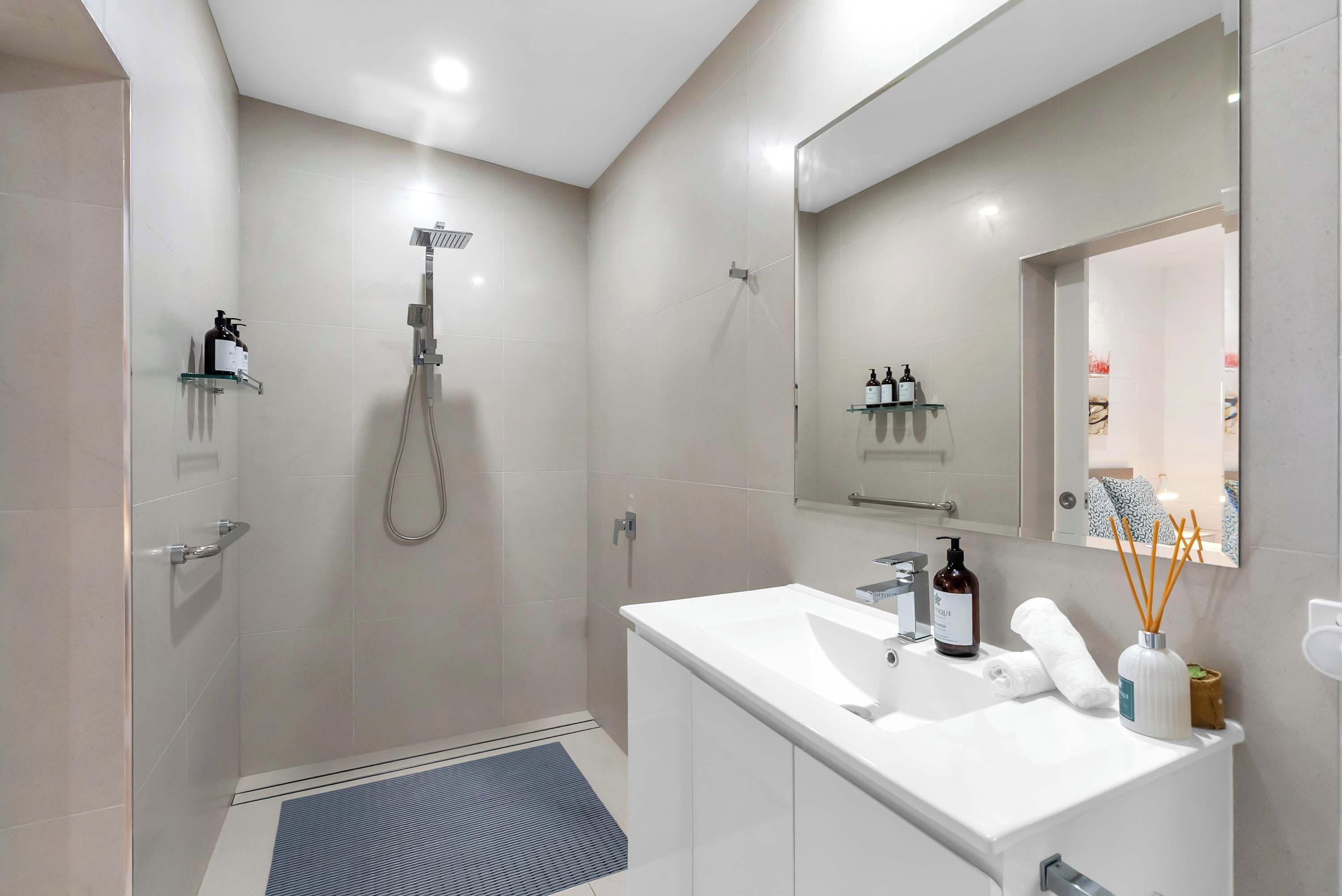 A modern bathroom with a shower, a sink, and a mirror.