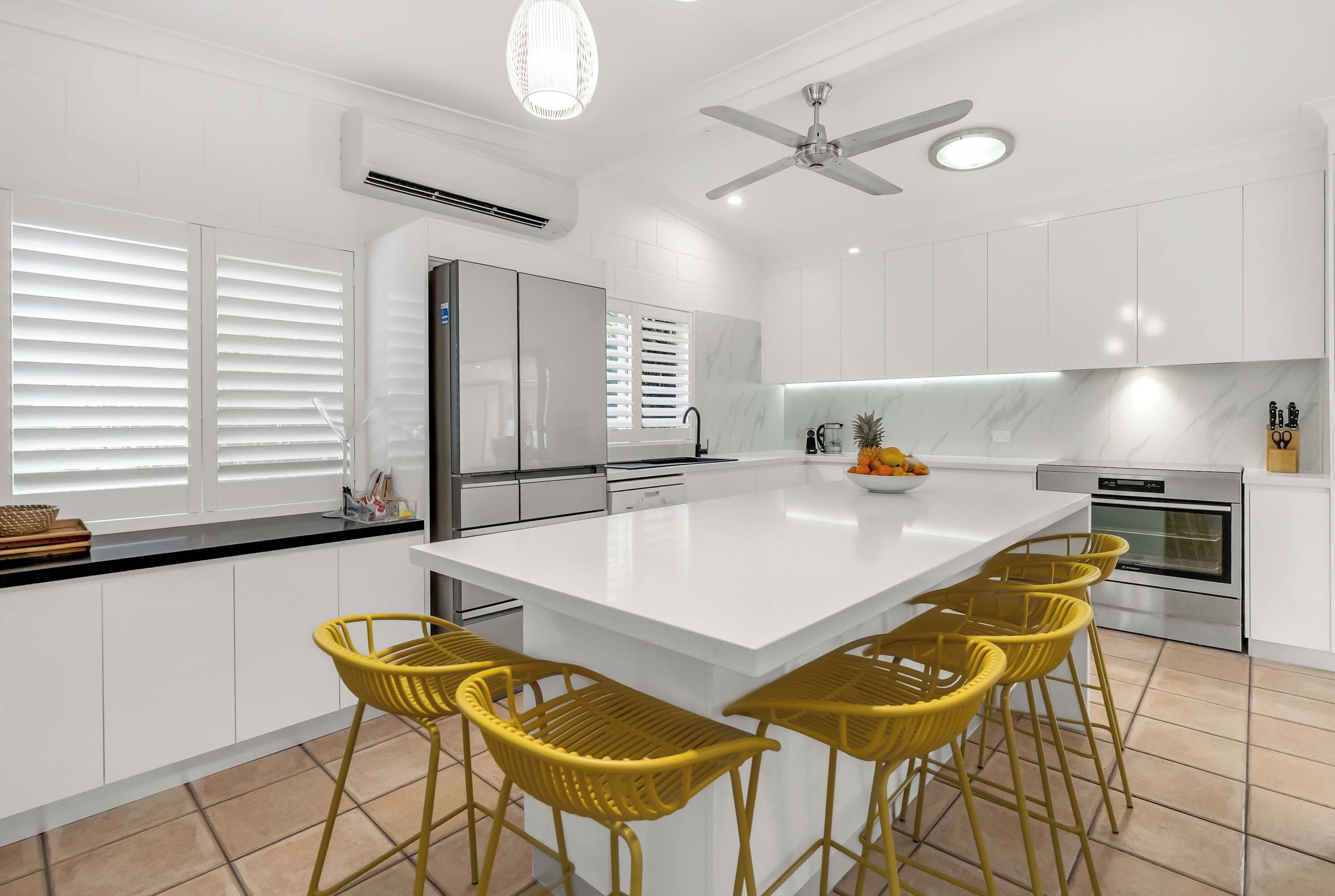 Une cuisine moderne dotée d’un grand îlot central, de meubles blancs et d’un four encastré.