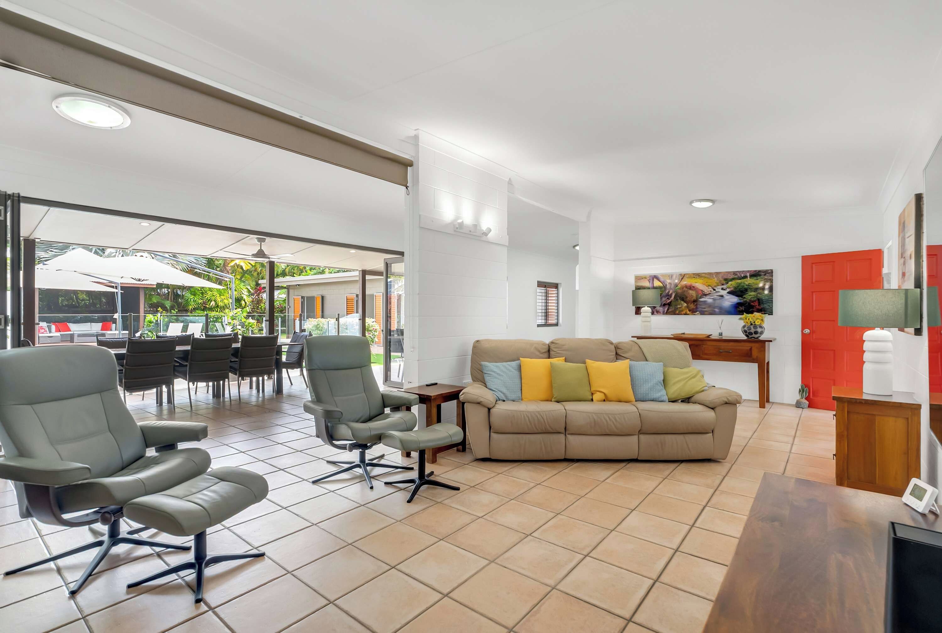 Un grand espace de vie comprenant un canapé, des fauteuils et un coin repas avec des tables et des chaises.