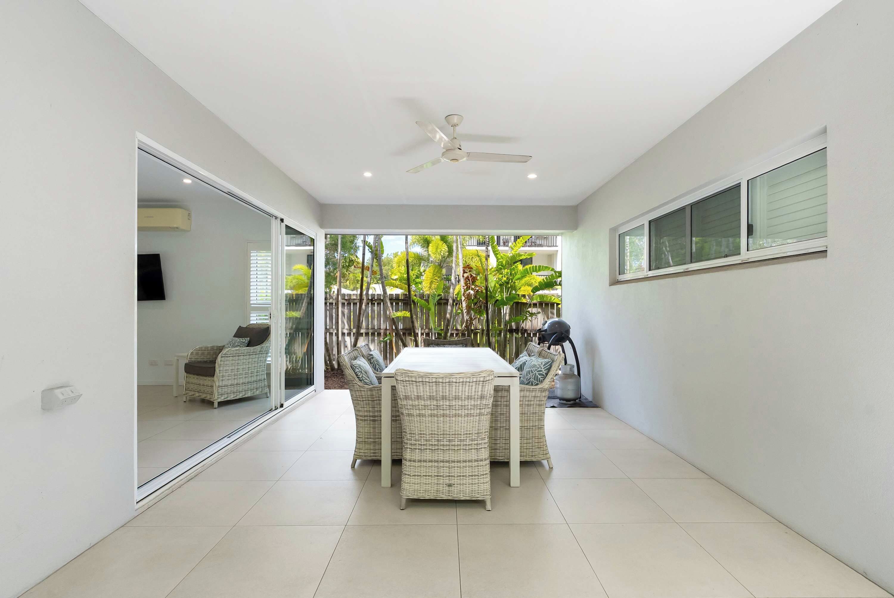 Une terrasse moderne avec une table à manger, des chaises et un ventilateur de plafond.