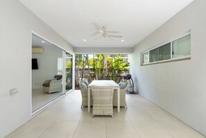 A modern patio with a dining table, chairs, and a ceiling fan.