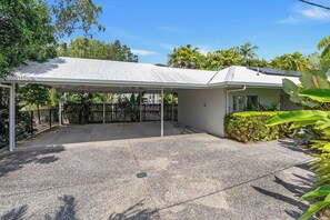A covered outdoor area with a gravel driveway, a metal fence, and a building with a white exterior and a sloped roof. - The Last Resort - Villa 1 (Palm Cove)