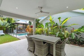 A patio with a table and chairs, surrounded by lush tropical plants.