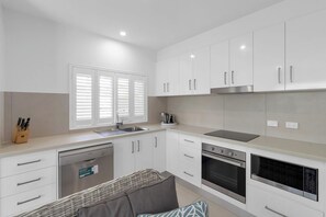 A modern kitchen with white cabinets, stainless steel appliances, and a built-in dishwasher.