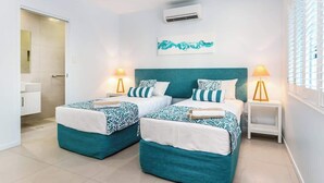 Une chambre d’hôtel avec deux lits, un ventilateur de plafond, un appareil de climatisation et une fenêtre avec des stores.