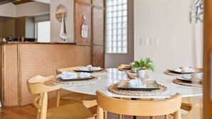 A dining area with a round table, wooden chairs, and a potted plant.