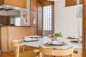 Un comedor con una mesa redonda, sillas de madera y una planta en maceta.