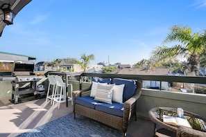 Relax on the balcony with a wicker sofa and chair, perfect for reading a book or enjoying the view of the surrounding neighborhood.