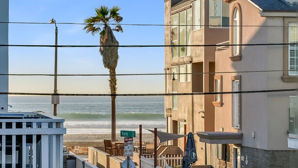 Propiedad frente a la playa con vista al océano, una palmera y un letrero de 'No Estacionar'.