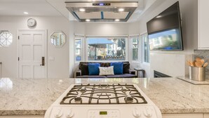 Una cocina moderna con estufa a gas, un reloj digital y un amplio ventanal con vistas al exterior.