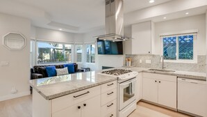 Una cocina moderna con una isla central, horno empotrado y campana extractora de acero inoxidable.