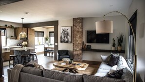 Un salon moderne avec un canapé, une table basse et un coin repas équipé de tabourets de bar.