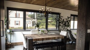 Un espace repas avec une table en bois, des bancs et un lustre.