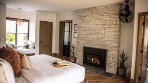 Une chambre avec un grand lit, une cheminée et une vue sur l’extérieur.