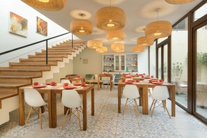 A dining area with multiple tables and chairs, a staircase, and large windows. - Hotel Boutique Lambassade Bellavista (Santiago)