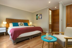 A hotel room with a bed, bedside tables, a chair, a small table, and a door. - Hotel Boutique Lambassade Bellavista (Santiago)