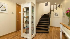 A staircase with wooden steps and a white railing, leading to a landing with a white cabinet with glass doors.