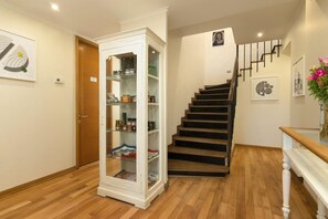 A staircase with wooden steps and a white railing, leading to a landing with a white cabinet with glass doors. - Hotel Boutique Lambassade Bellavista (Santiago)