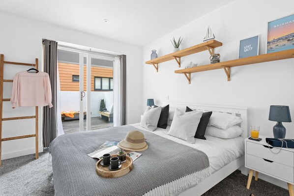 Ein modernes Schlafzimmer mit Bett, Nachttischen, einem Kleiderschrank und Blick ins Freie.