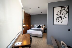 A modern bedroom with a bed, bedside tables, a desk, and a chair. - Punto Lofts Periférico Sur (Mexico City)
