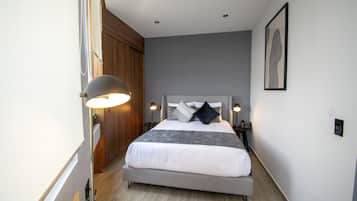 Un dormitorio con cama, lámparas de noche, un armario de madera y un cuadro en la pared.