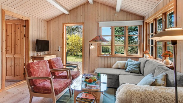 A cozy wooden interior with a sofa, chairs, a TV, and a dining table with a fruit bowl. - Stunning home in Fårevejle with WiFi (Fårevejle)