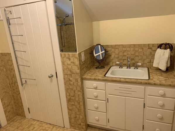 A bathroom with a white door, a shower with a glass enclosure, a sink with a mirror, and a towel rack. - Family friendly lakefront property on large wilderness estate with sandy beach (Land O' Lakes)