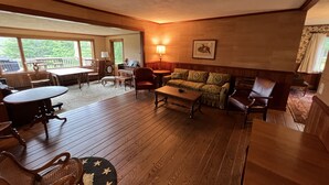 Una sala de estar acogedora con suelo de madera, un piano, un sofá y una mesa de comedor.