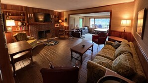 Un salón acogedor con chimenea, muebles de madera y vistas al exterior.