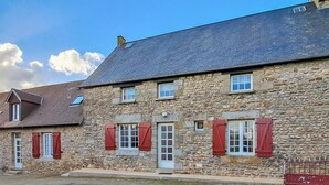 A stone building with multiple windows, some with shutters, and a sloped roof. - 3 bedroom stunning home in Saint-Brice-de-Landell (Saint-Brice-de-Landell)