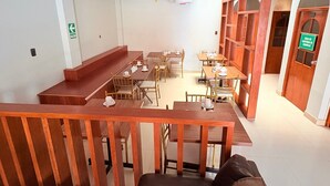A cafe with wooden tables and chairs, a staircase, and a sign indicating a storage area. - Baños del Inca Hotel (Baños del Inca)