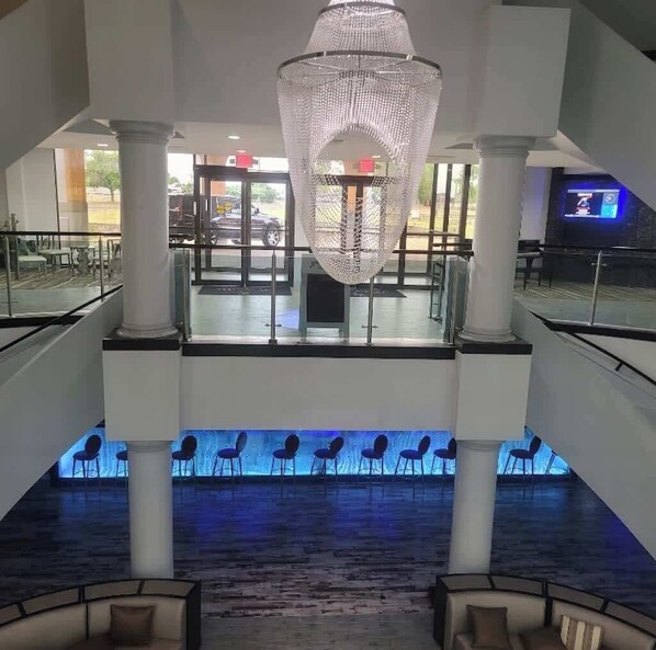A spacious lobby with a large chandelier, multiple seating areas, and a view of the outside through large windows.